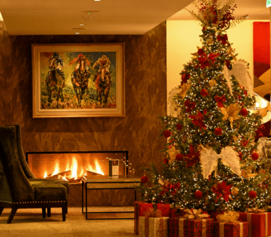 Cosy hotel lobby with festive Christmas tree, warm fireplace, and elegant seating, perfect for a holiday stay.