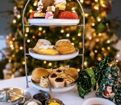Afternoon tea setup with pastries by Christmas tree, festive ambiance, holiday getaway.