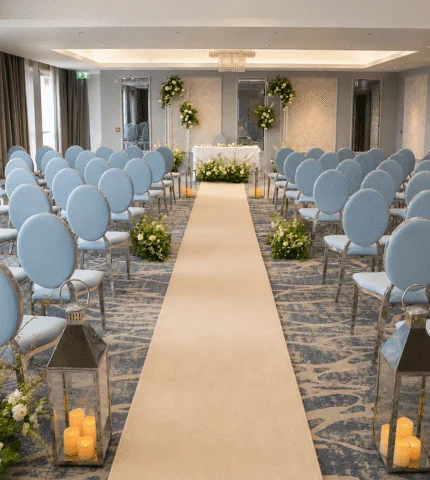 Elegant wedding venue with blue chairs, aisle runner, floral displays, perfect for memorable ceremonies.