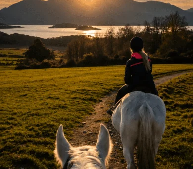 Guests enjoying horse riding at sunset with stunning mountain and lake views.