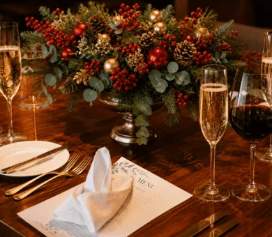 Elegant festive dining table with champagne and wine glasses, ornate centrepiece, menu, and fine cutlery at luxury hotel.
