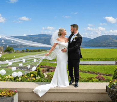Bride and groom on manicured lawn with mountain and lake views, showcasing beautiful garden wedding venue at luxury hotel.