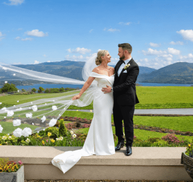 Bride and groom on manicured lawn with mountain and lake views, showcasing beautiful garden wedding venue at luxury hotel.
