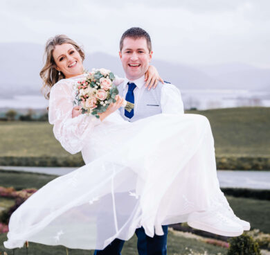 Bride and groom in lush garden with lake and mountain views, ideal wedding venue, romantic setting, Cambridgeshire hotel.