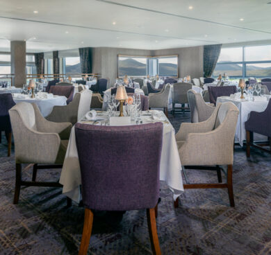 Elegant dining area with mountain views, featuring plush chairs, set tables, and ambient lighting for a chic dining experience.