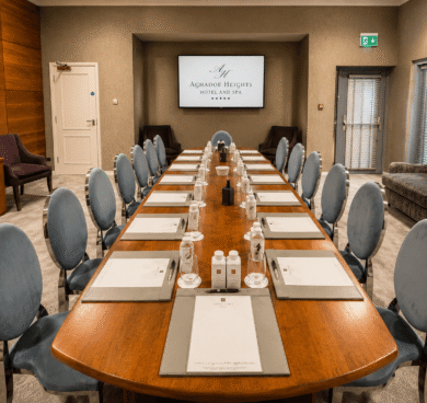 Elegant conference room with long polished table and blue chairs, equipped with notepads, pens, and water bottles.