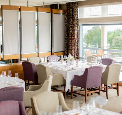 Elegant hotel dining room with sea view, featuring stylish tables, plush chairs, and natural light, perfect for gatherings.