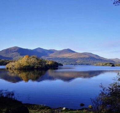Serene lake view with lush islands and distant mountains under a clear blue sky near the hotel resort.
