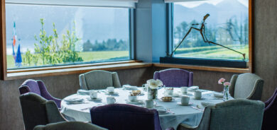 Elegant dining area with mountain views, cosy chairs, and a table set for guests at a luxury hotel.