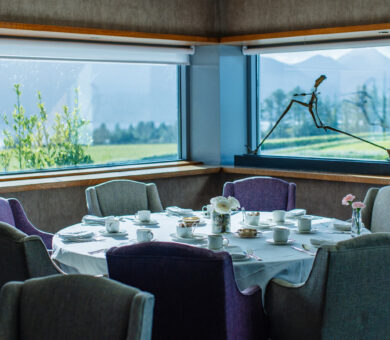 Elegant dining area with mountain views, cosy chairs, and a table set for guests at a luxury hotel.