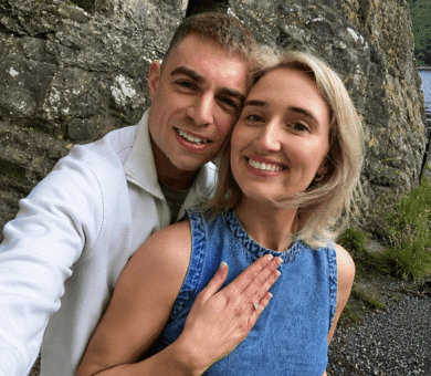 Smiling couple enjoying scenic rocky lakeside view, showcasing natural beauty and tranquility near hotel. Perfect getaway.