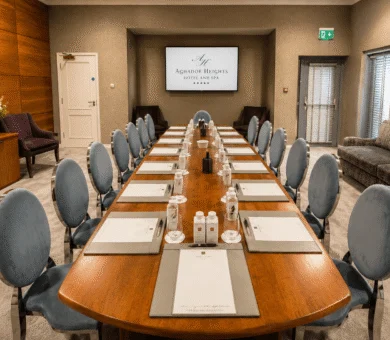 Elegant hotel conference room with large wooden table, plush chairs, and modern amenities, perfect for business events.