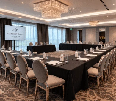 Modern conference room with U-shaped table, elegant chandeliers, and panoramic windows at Aghradane Heights Hotel.