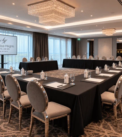 Modern conference room with U-shaped table, elegant chandeliers, and panoramic windows at Aghradane Heights Hotel.